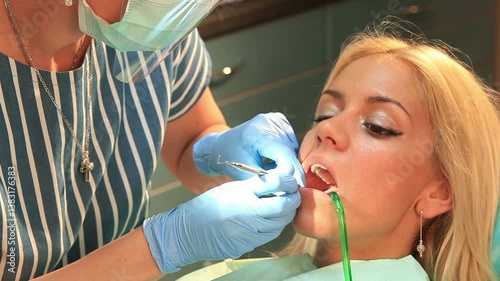 Dentist using ultraviolet lamp for teeth whitening procedure on female patient