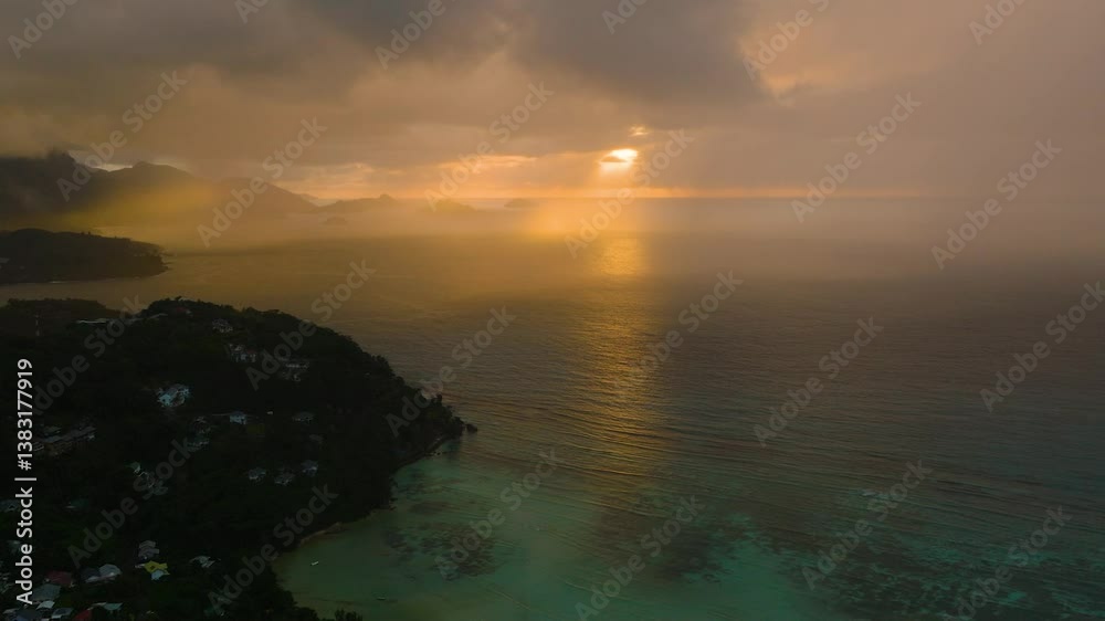 Golden sunset with dark clouds hanging over the tranquil ocean, casting a serene reflection. Seychelles, Mahe. Golden sunset with dark clouds hanging over the tranquil ocean, casting a serene reflection. Seychelles, Mahe.