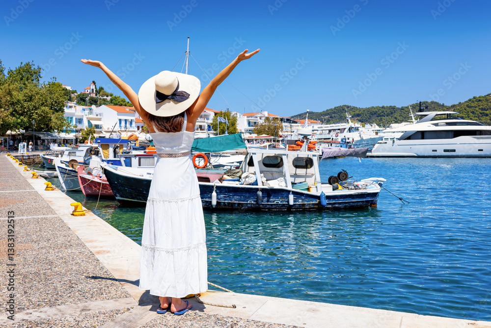 A happy tourist woman looks at the old port of Skiathos island, Greece, during summer time