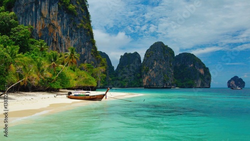 A lone boat sits peacefully on the shore of a sandy beach, surrounded by calm waters and warm sunlight