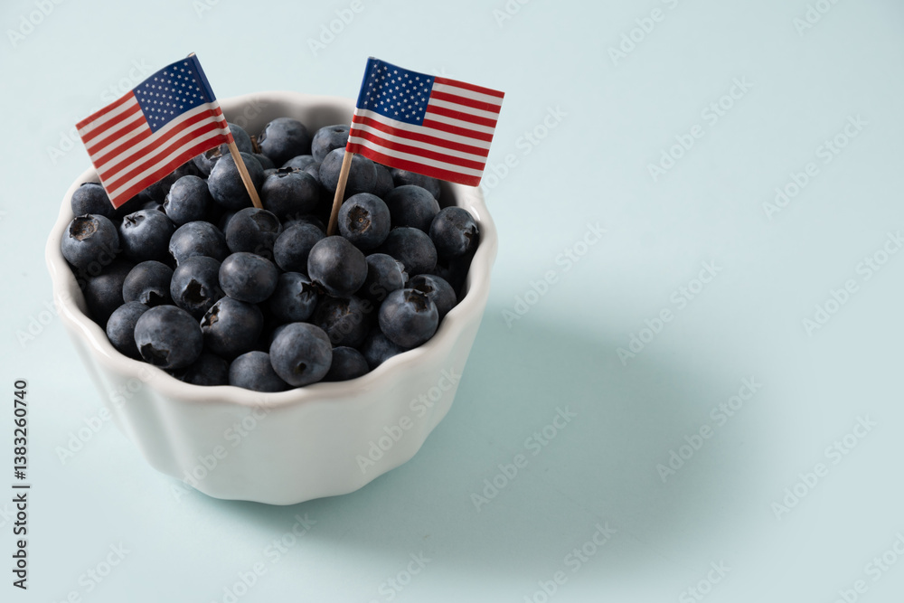 Blueberry decorated two US flags in white bowl on blue background. Concept preparations for Patriotic Independence Day 4th of july. Close up. Copy space.