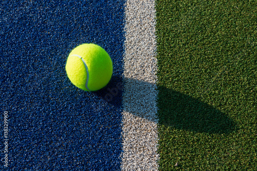 Close-up of tennis ball on blue/green synthetic court.