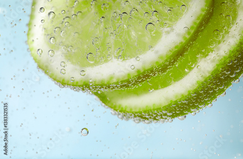 Foto Soda water with lime slices against light blue background, closeup