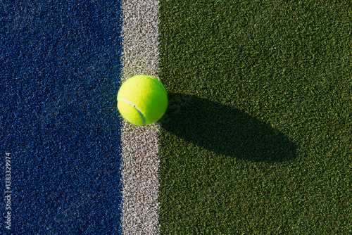 Close-up of tennis ball on blue/green synthetic court.