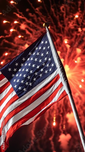 Fireworks explode behind waving American flag. 4th of July celebration