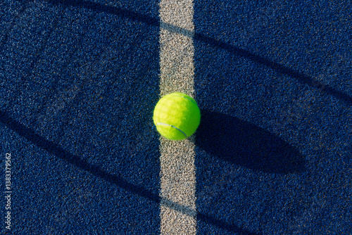 Close-up of Tennis Ball on blue/green synthetic court with shadow of tennis racket