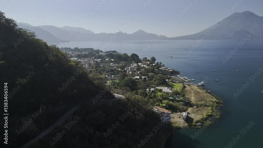 Drone flies right peaking out from behind a mountain to reveal Panajachel, Guatemala on Lake Atitlan on a sunny morning Drone flies right peaking out from behind a mountain to reveal Panajachel, Guatemala on Lake Atitlan on a sunny morning