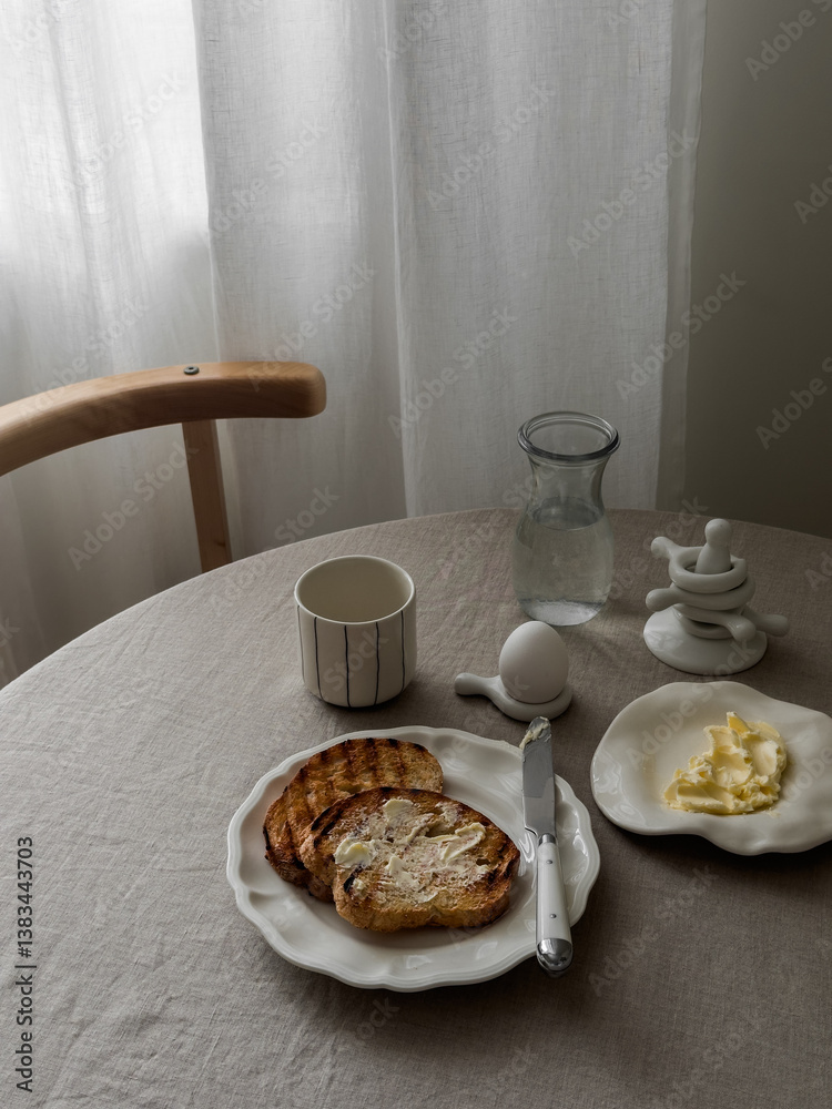 A simple and delicious breakfast - toasts with butter, boiled egg, coffee on a round table A simple and delicious breakfast - toasts with butter, boiled egg, coffee on a round table