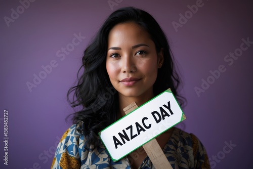 A young woman with a gentle smile holds a sign reading 'COMMEMORATION DAY' against a softly colored background