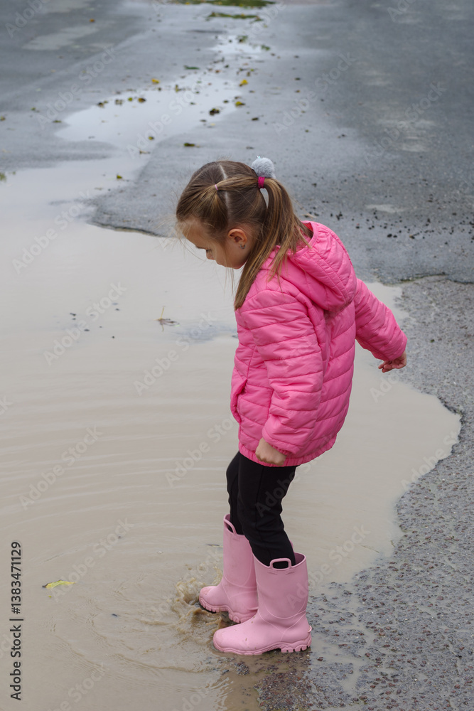 Girl playing in a puddle of water after rain