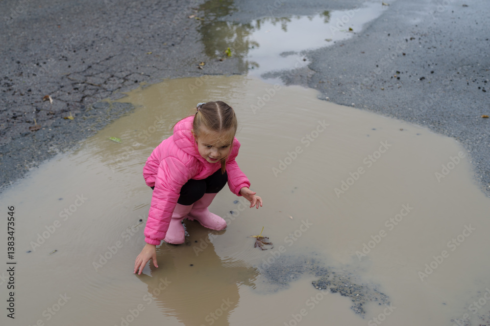 Girl playing in a puddle of water after rain