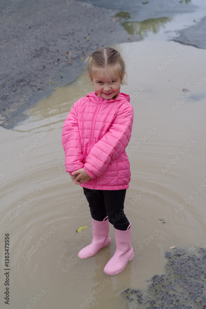 Girl playing in a puddle of water after rain