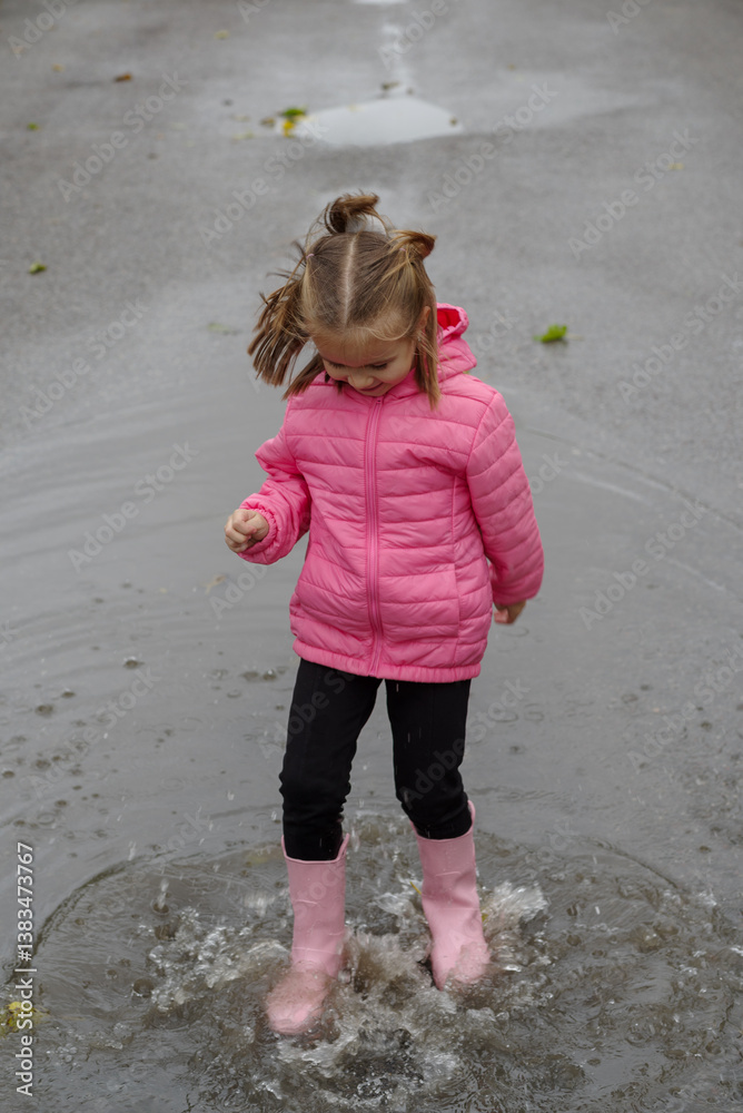 Girl playing in a puddle of water after rain