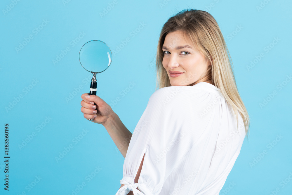 Studio portrait of woman with magnifying glass. Model with excitement holding magnifying glass and looking at camera. Blue studio background with copy space Studio portrait of woman with magnifying glass. Model with excitement holding magnifying glass and looking at camera. Blue studio background with copy space