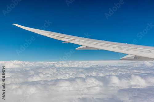 Obraz na płótnie Left (port) wing of a Boeing 787-9 set against a blue sky over white clouds seen from the passenger window somewhere near Hong Kong w salonie