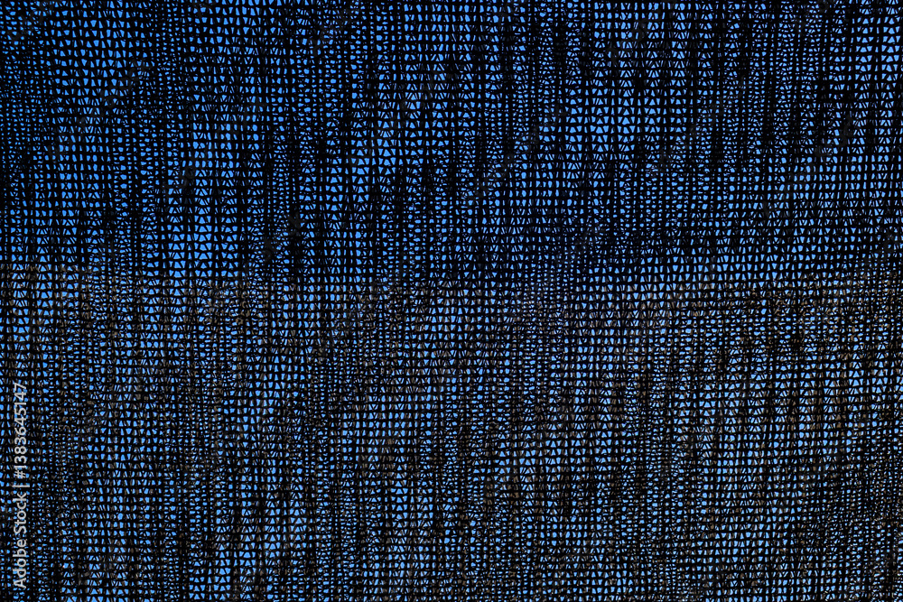 Close-up of black shading mesh against a blue sky. Commonly used in agriculture to protect crops from sunlight