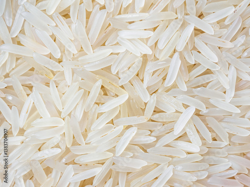 Close-up shot of dry, uncooked long grain basmati rice. Grains are slender and translucent, natural texture.