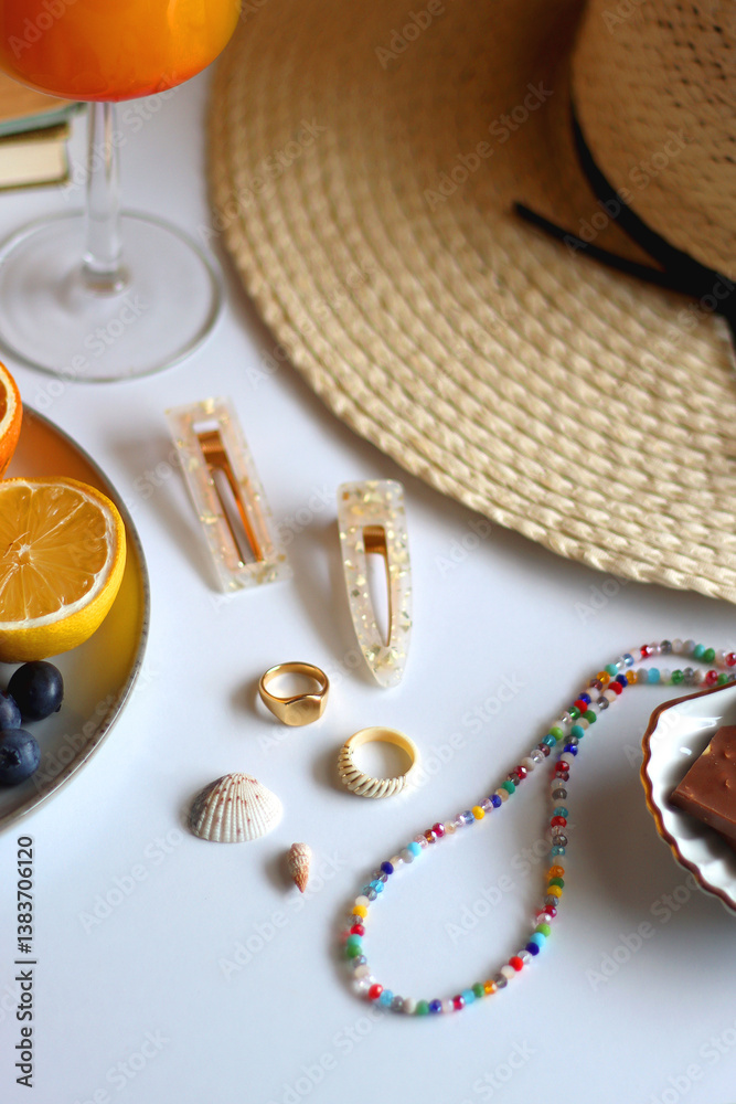Glass of cocktail, straw hat, sunglasses, books, fresh fruit, chocolate and accessories. Summer essentials on the table. Selective focus.