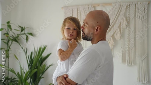 Father lovingly holds his young daughter in a cozy room at home. Concept of warm, moment, deep bond between parent and child, heartfelt expression of family and togetherness