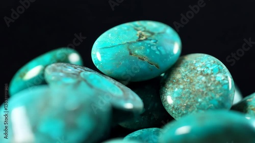Polished turquoise gemstones with varying shades of blue and green, showcasing their natural patterns and textures against a dark background. Mineral pattern macro.