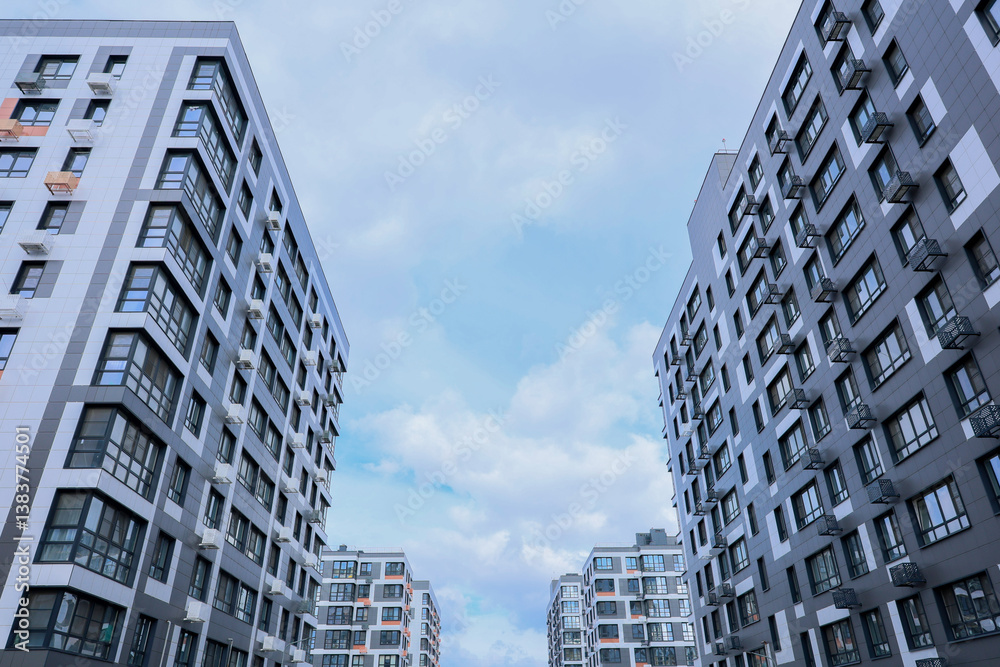 Fototapeta premium Contemporary apartment buildings beautifully framed by a serene sky that features soft, fluffy clouds above them