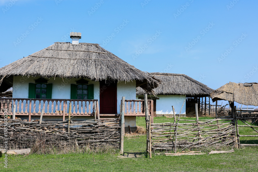 A picturesque view of a rustic house with a thatch roof, surrounded by lush greenery and vibrant nature A picturesque view of a rustic house with a thatch roof, surrounded by lush greenery and vibrant nature