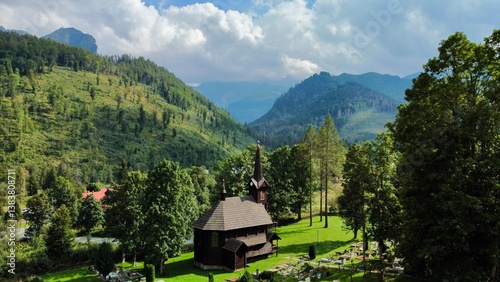 Stunning panoramic view of Church and Tatra mountains in Tatranska Javorina, Slovakia A picturesque scene of. wooden church nestled in lush green valley, surrounded by dense forest and rolling hills photo