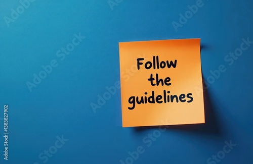 Orange sticker note with Follow the guidelines message, blue background. Concept of rules compliance, instruction, regulatory process, business, legal, education. Copy space for text.
