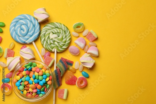 Many different tasty candies and marshmallows on yellow background, flat lay. Space for text