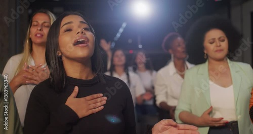 Women passionately singing and worshiping during church service, showcasing spirituality and faith, in a diverse community standing together in prayerful unity