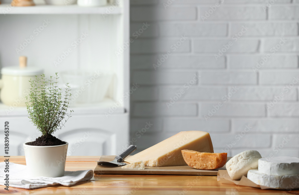 Different types of cheese, slicer and potted thyme on wooden table indoors. Space for text