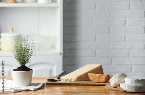 Obraz na płótnie Different types of cheese, slicer and potted thyme on wooden table indoors. Space for text w salonie