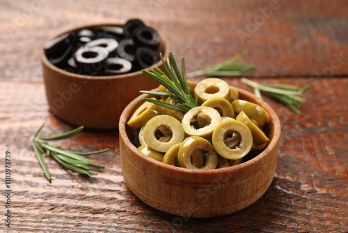 Wallpaper Mural Different delicious marinated olive rings and rosemary on wooden table, closeup Torontodigital.ca