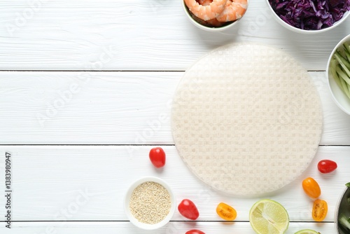 Rice paper sheets and different ingredients on white wooden table, flat lay. Space for text