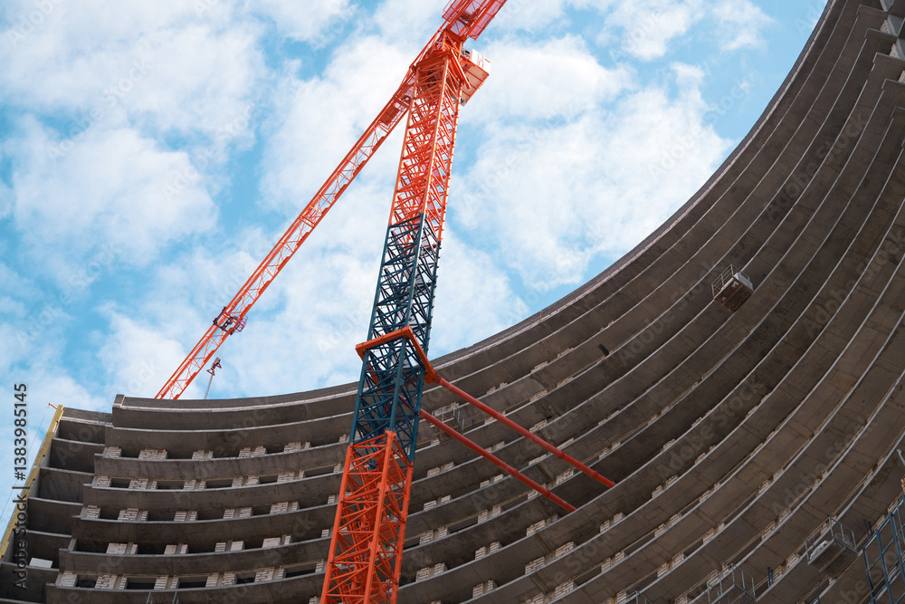 Monolithic construction of a skyscraper with a semicircular shape. A fragment of a building and a construction crane against the sky.