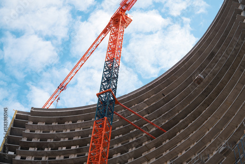 Obraz na płótnie Monolithic construction of a skyscraper with a semicircular shape. A fragment of a building and a construction crane against the sky. w salonie