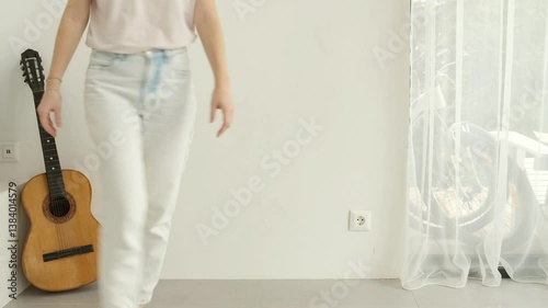 Young woman placing guitar and various houseplants on the floor at home. Houseplants support human health in homes. Green home concept