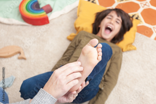 Fototapete Playful child laughing while his mother tickles his feet – overhead view