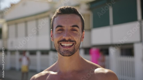 Portrait looking at camera of young caucasian guy people in swimwear laughing posing for a picture on the beach. Men under the sunny sky enjoying leisure time and summer travel. Millennial people