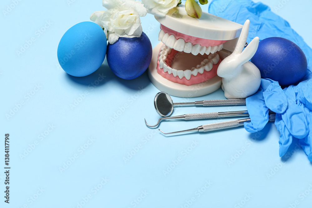 Dental tools with jaw model, flowers and Easter eggs on blue background, closeup