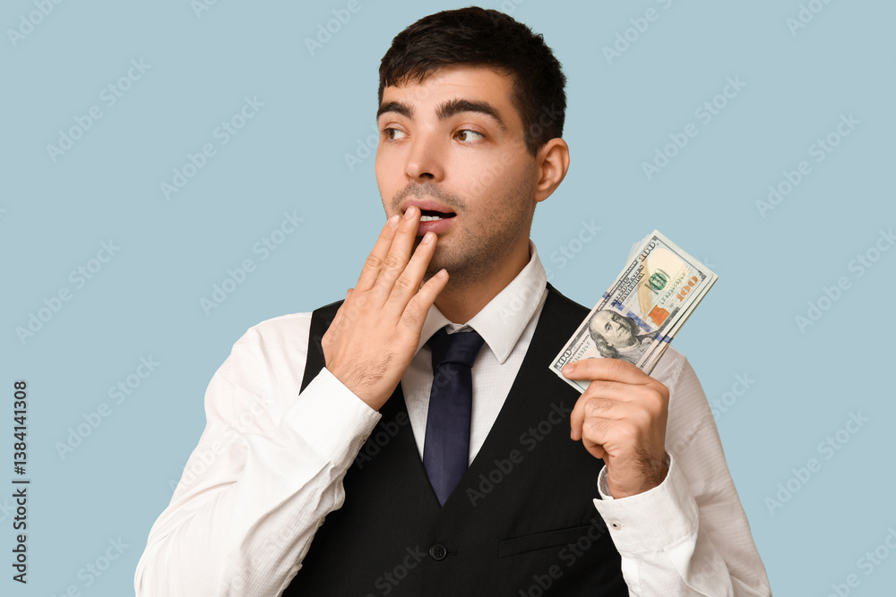 Shocked young businessman with bribe on blue background, closeup Shocked young businessman with bribe on blue background, closeup