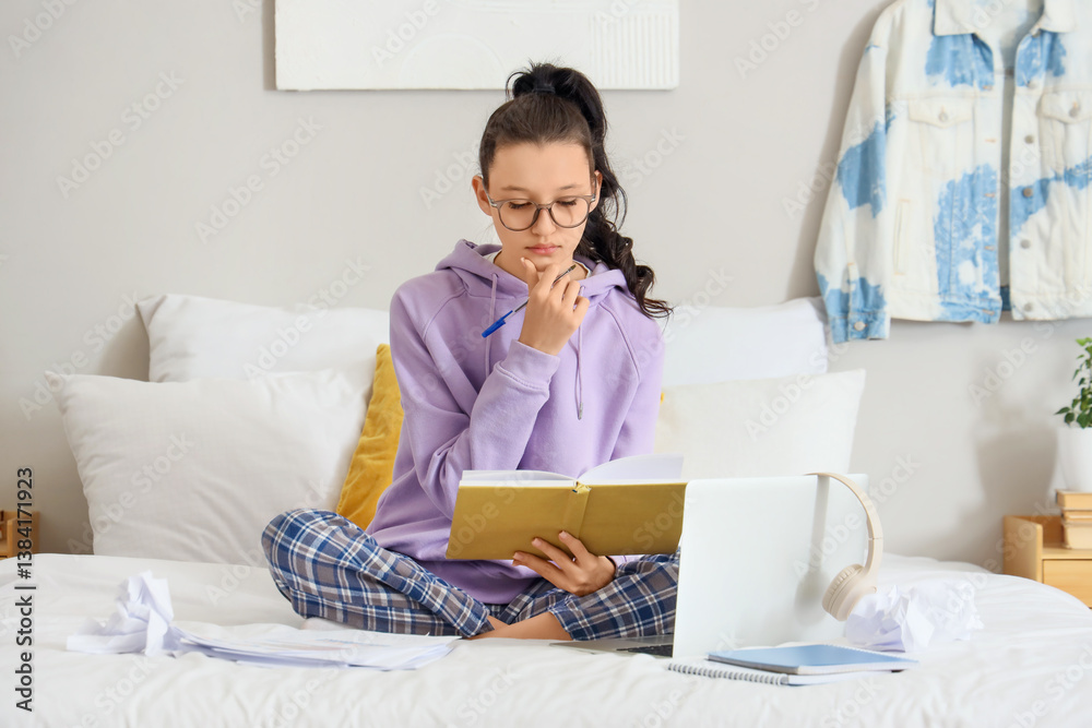 Thoughtful teenage girl with notebook and laptop working online in bedroom Thoughtful teenage girl with notebook and laptop working online in bedroom