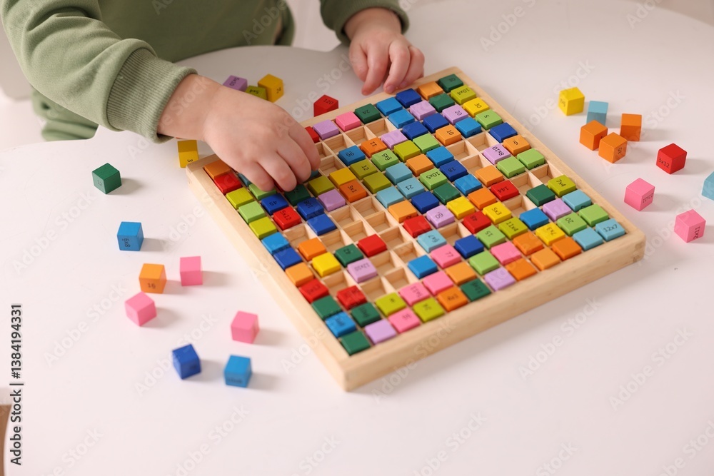 Motor skills development. Little boy playing with Times table tray indoors, closeup Motor skills development. Little boy playing with Times table tray indoors, closeup