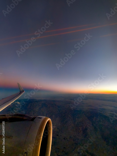 Obraz na płótnie Looking out the window of an airplane with partial wing and engine view with dramatic landscape and sky w salonie