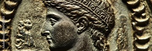 Ancient coin featuring a profile portrait with a wreath on a textured background.