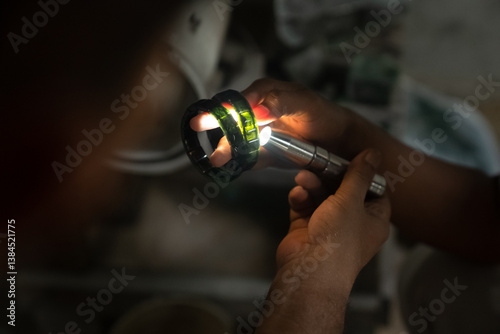 A craftsman shines a light on a piece of jade to see its clarity. A skilled craftsman cuts jade to make jewelry. Jade cutting process by an Asian craftsman