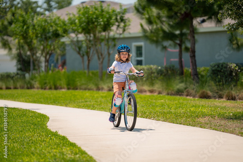 Obraz na płótnie Kid riding bike in a helmet. Child with a childs bike and in protective helmet. Happy kid boy having fun in summer park with a bicycle. Bike helmet, bicycle safety, cycling accessories. w salonie