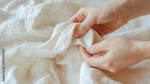 Close up of hands gently folding soft, textured fabric, showcasing delicate details and craftsmanship involved in laundry care. image evokes sense of warmth and comfort