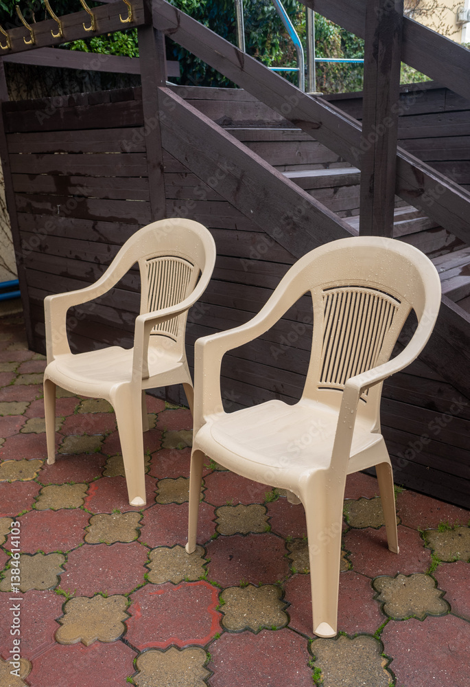 Two plastic chairs are sitting on a brick patio Two plastic chairs are sitting on a brick patio