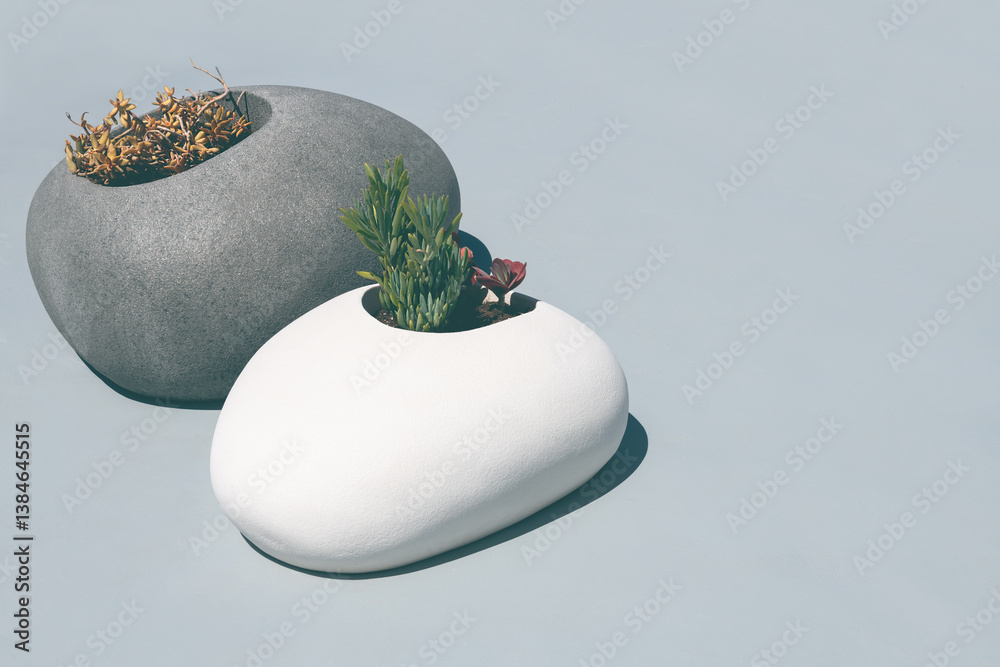 Grey and white decorative ceramic pots with flowers on the rooftop.